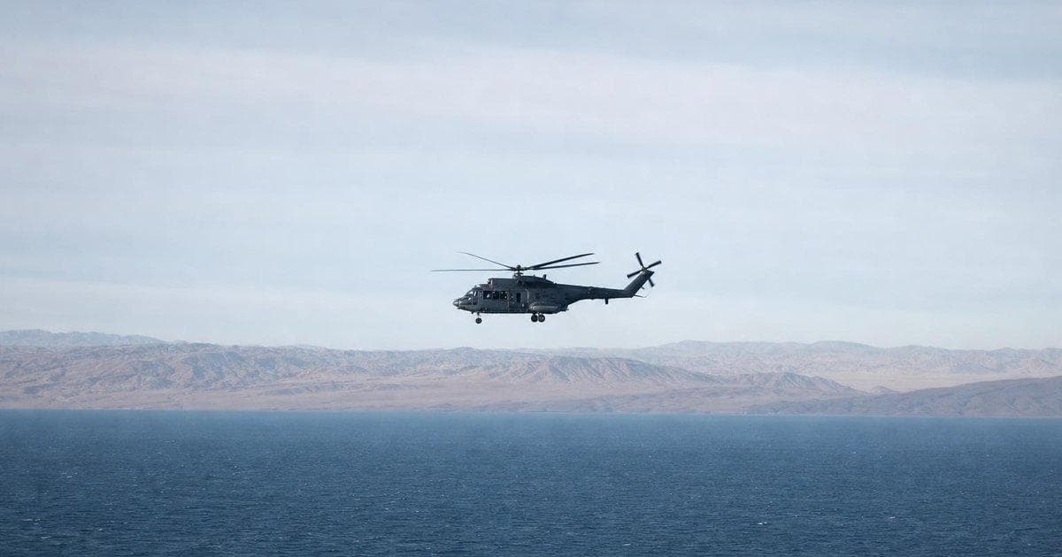 Military helicopter over water near desert coast as markets react to Gulf tensions, defense and oil stocks in focus